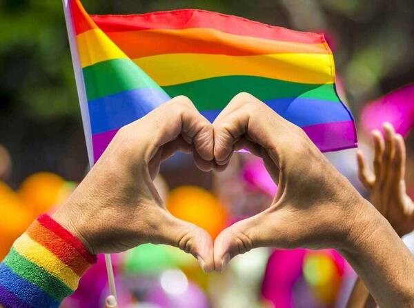 supporting-hands-make-heart-sign-and-wave-in-front-of-a-rainbow